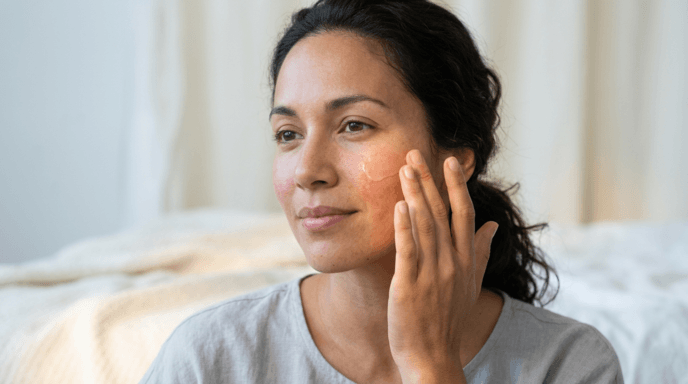 Woman gently patting niacinamide serum onto reddish cheeks