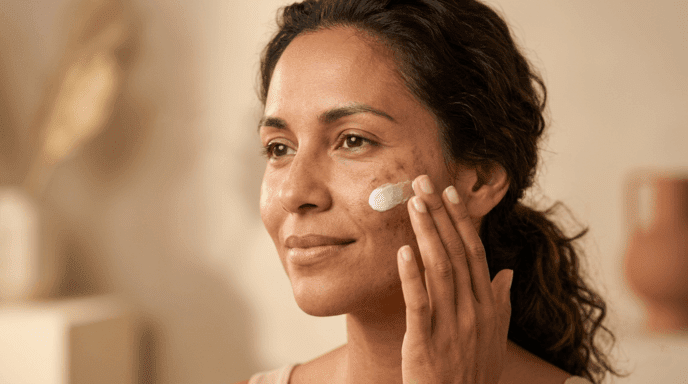 Woman with medium-dark skin applying azelaic acid cream